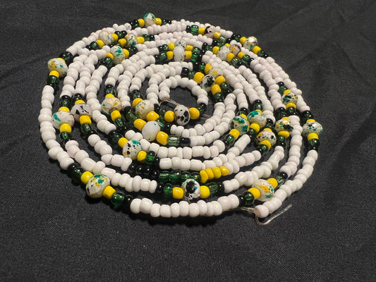 waist beads with white, green, and yellow beads on a black background