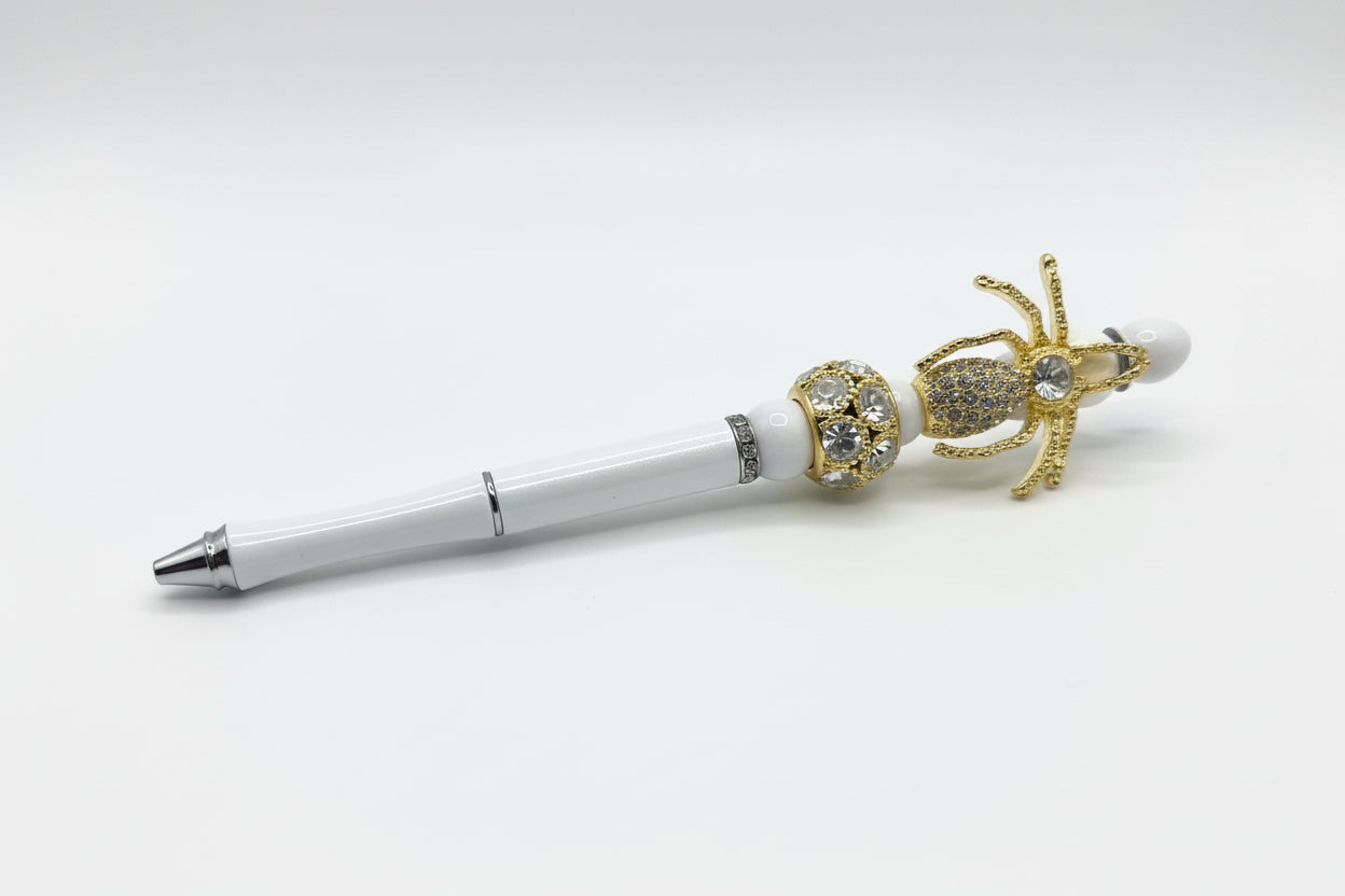 Handcrafted white beaded pen with a gold and crystal spider charm by E-monae Jewels.