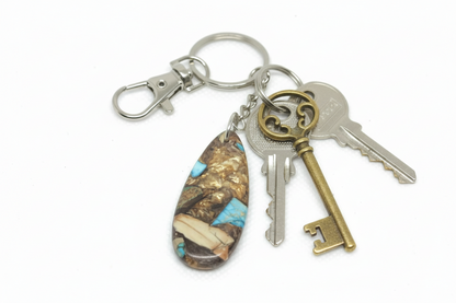 Handcrafted teardrop-shaped composite turquoise gemstone keychain with a copper-tone matrix on a silver keyring with vintage-style brass keys.